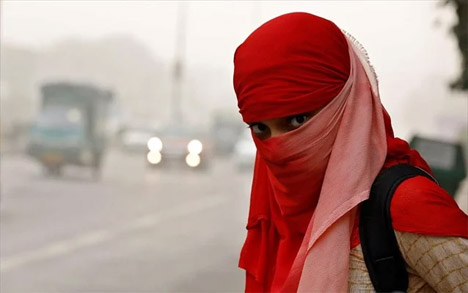 Μία γυναίκα στο Νέο Δελχί περιμένει το λεωφορείο έχοντας καλύψει με μαντήλι το πρόσωπό της για να προστατευτεί από το νέφος που υπάρχει στην πόλη και οδηγεί πολλές φορές σε λήψη μέτρων όπως το κλείσιμο των σχολείων. - REUTERS/SAUMYA KHANDELWAL